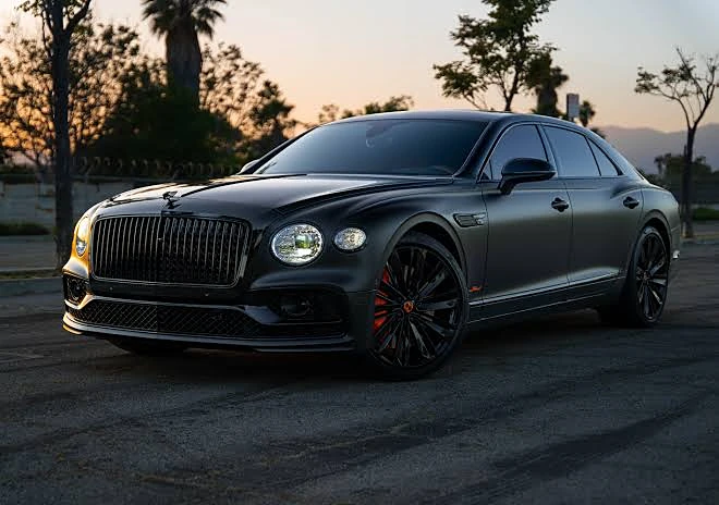 Blacked-out Bentley Flying Spur at dusk with dark tinted windows